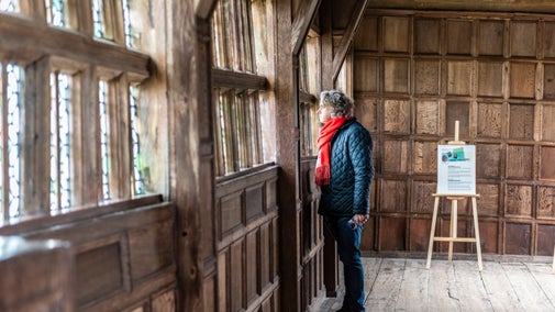 A visitor looks through the window of the Long Gallery at Little Moreton Hall, Cheshire
